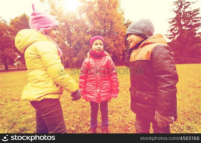 childhood, leisure, friendship and people concept - group of happy kids talking in autumn park