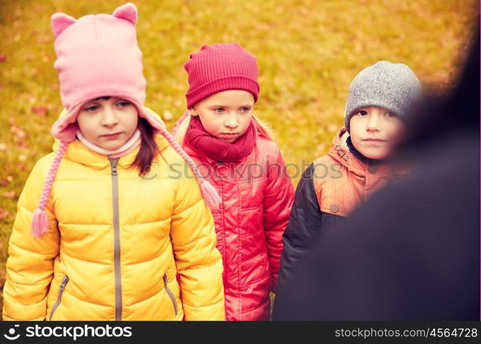 childhood, leisure, friendship and people concept - group of sad kids being blamed for misbehavior in autumn park