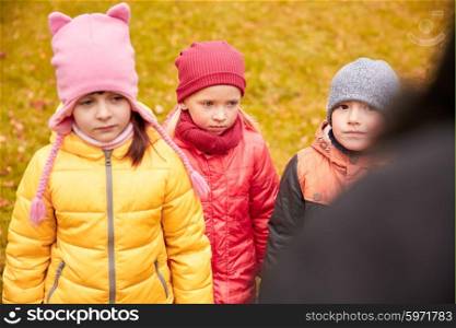 childhood, leisure, friendship and people concept - group of sad kids being blamed for misbehavior in autumn park