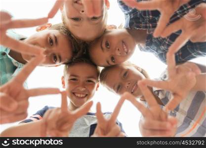 childhood, leisure, friendship and people concept - group of smiling happy children showing v sign in circle