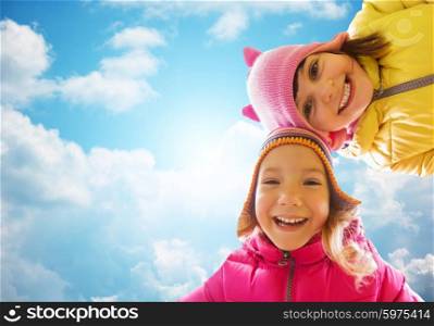 childhood, leisure, friendship and people concept - happy girls faces outdoors over blue sky and clouds background