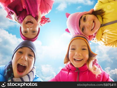 childhood, leisure, friendship and people concept - happy little children faces outdoors over blue sky and clouds background