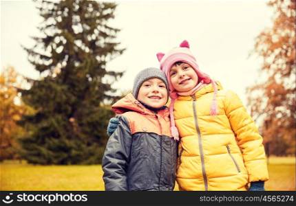 childhood, leisure, friendship and people concept - happy little girl and boy in autumn park