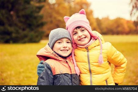 childhood, leisure, friendship and people concept - happy little girl and boy in autumn park