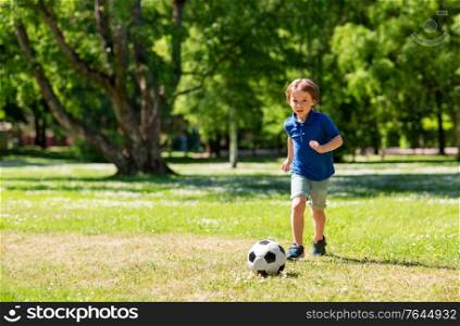 childhood, leisure games and people concept - happy little boy with ball playing soccer at summer park. happy little boy with ball playing soccer at park