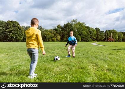 childhood, leisure games and people concept - happy little boy with ball playing soccer at summer park. happy little boys with ball playing soccer at park