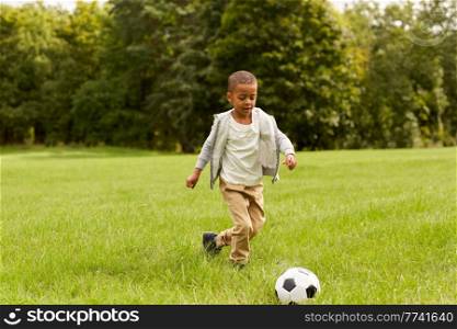 childhood, leisure games and people concept - little boy with ball playing soccer at summer park. little boy with ball playing soccer at park