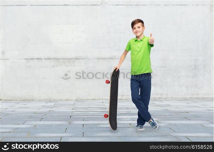childhood, leisure, school and people concept - happy smiling boy with skateboard showing thumbs up over concrete gray wall on city street background