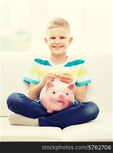 childhood, money, investment and happy people concept - smiling little boy with piggy bank and money at home