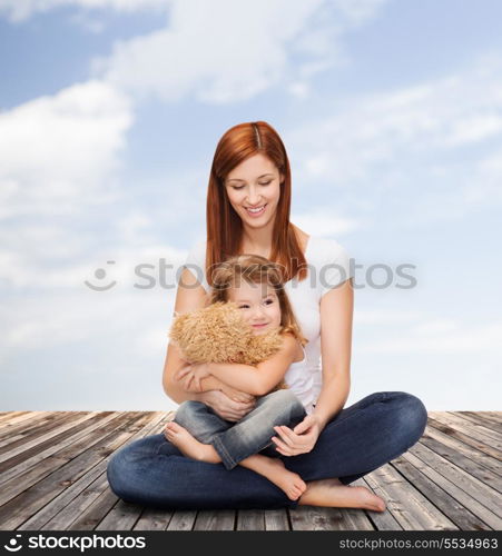 childhood, parenting and relationship concept - happy mother with adorable little girl and teddy bear