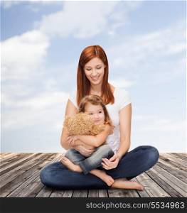 childhood, parenting and relationship concept - happy mother with adorable little girl and teddy bear