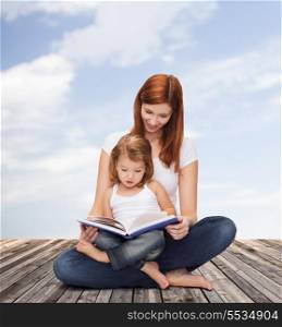childhood, parenting and relationship concept - happy mother with adorable little girl reading book