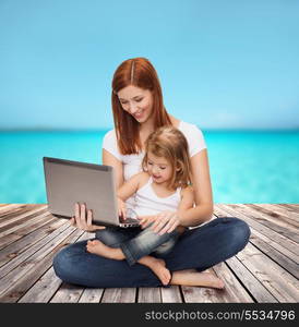 childhood, parenting and technology concept - happy mother with adorable little girl with laptop