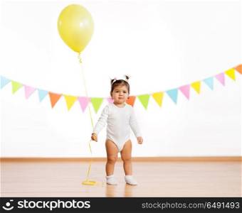 childhood, people and celebration concept - baby girl with helium balloons on birthday party. baby girl with balloons on birthday party. baby girl with balloons on birthday party