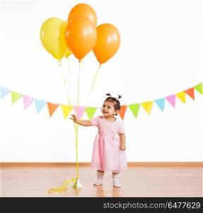 childhood, people and celebration concept - happy baby girl with helium balloons on birthday party. happy baby girl with balloons on birthday party. happy baby girl with balloons on birthday party