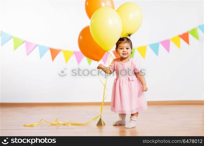 childhood, people and celebration concept - happy baby girl with helium balloons on birthday party. happy baby girl with balloons on birthday party. happy baby girl with balloons on birthday party