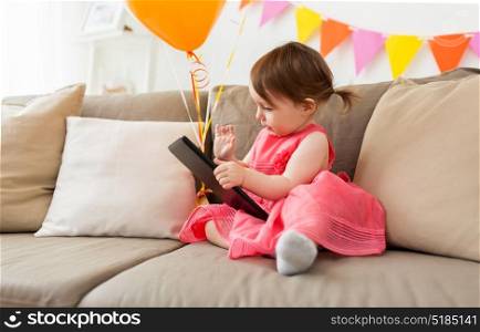 childhood, people and celebration concept - happy baby girl with tablet pc computer on birthday party at home. baby girl with tablet pc on birthday party at home