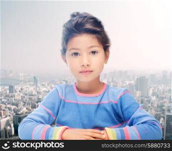childhood, people and happiness concept - little student girl over city background