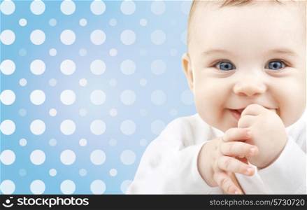 childhood, people and happiness concept - smiling baby boy face over blue and white polka dots pattern background