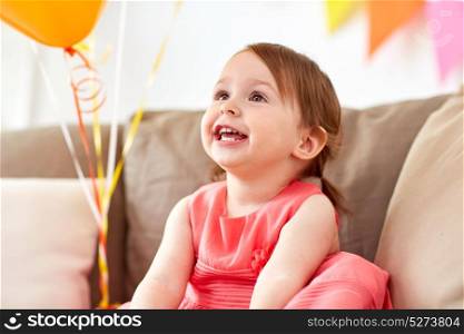childhood, people and holidays concept - happy baby girl on birthday party at home. happy baby girl on birthday party at home