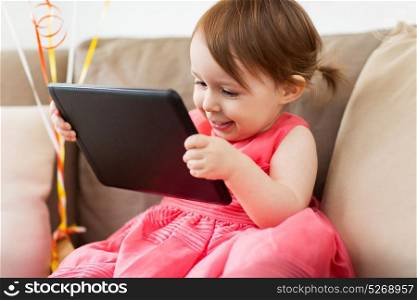 childhood, people and technology concept - happy baby girl with tablet pc computer at home. baby girl with tablet pc at home