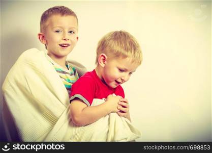 Childhood, relationship between brothers concept. Two little boys siblings playing together with towels and having fun.. Two little boys siblings playing with towels