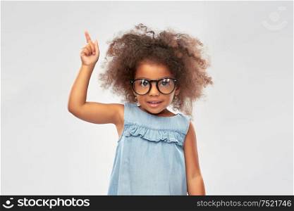 childhood, school and education concept - happy little african american girl in glasses over grey background. happy little african american girl in glasses