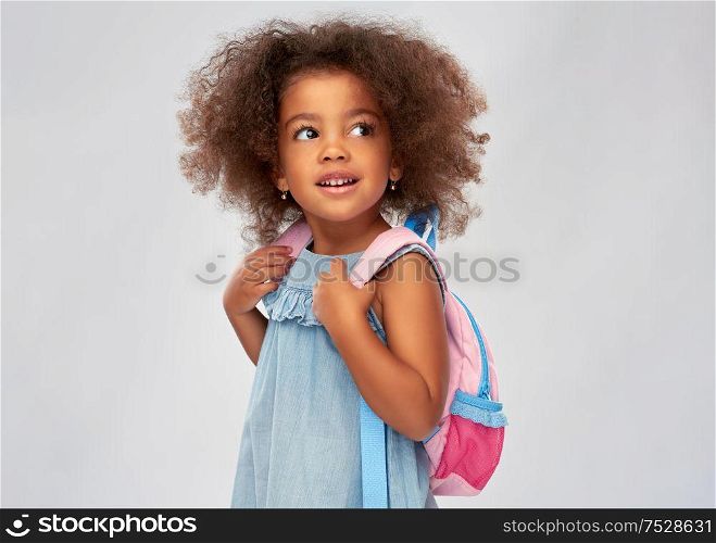 childhood, school and education concept - happy little african american girl with backpack over grey background. happy little african american girl with backpack
