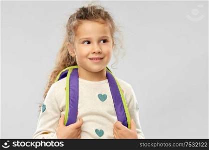 childhood, school and education concept - happy little girl with backpack over grey background. happy little girl with school backpack