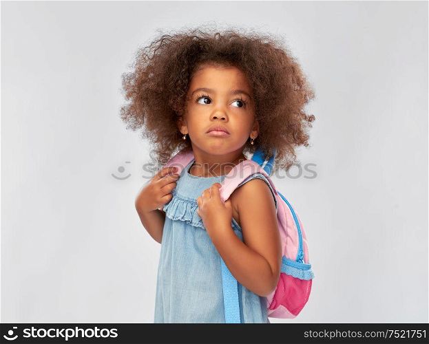 childhood, school and education concept - sad little african american girl with backpack over grey background. sad little african american girl with backpack