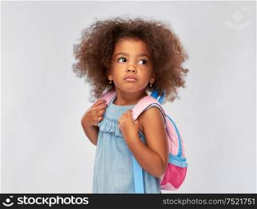 childhood, school and education concept - sad little african american girl with backpack over grey background. sad little african american girl with backpack