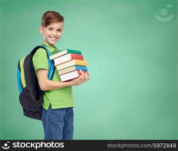 childhood, school, education and people concept - happy smiling student boy with school bag and books over green school chalk board background