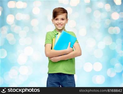 childhood, school, education and people concept - happy smiling student boy with folders and notebooks over blue holidays lights background