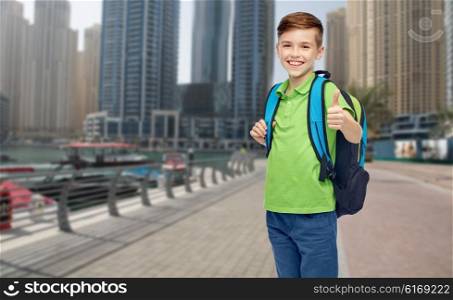 childhood, school, education and people concept - happy smiling student boy with school bag over dubai city street background