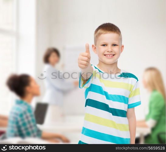 childhood, school, education and people concept - smiling little boy showing thumbs up over group of students in classroom