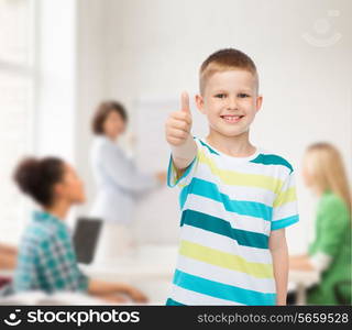 childhood, school, education and people concept - smiling little boy showing thumbs up over group of students in classroom