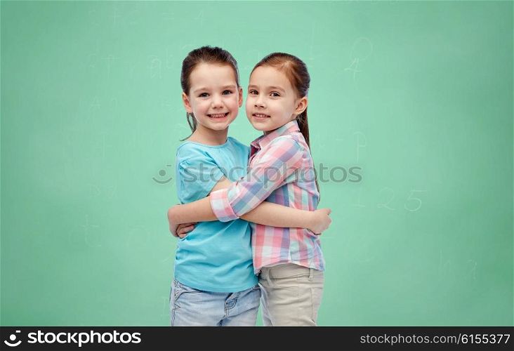 childhood, school, education, friendship and people concept - happy smiling little girls hugging over green chalk board background