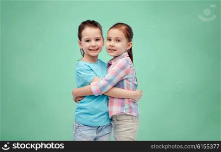 childhood, school, education, friendship and people concept - happy smiling little girls hugging over green chalk board background