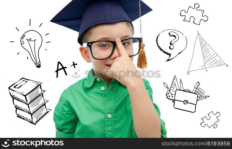childhood, school, education, knowledge and people concept - happy boy in bachelor hat or mortarboard and eyeglasses over doodles