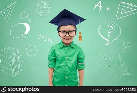 childhood, school, education, knowledge and people concept - happy boy in bachelor hat or mortarboard and eyeglasses over doodles on green chalk board background