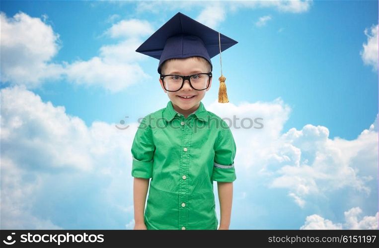 childhood, school, education, learning and people concept - happy boy in bachelor hat or mortarboard over blue sky and clouds background