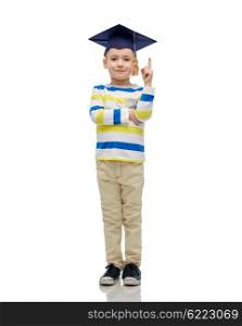 childhood, school, education, learning and people concept - happy boy in bachelor hat or mortarboard pointing finger up