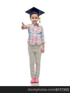 childhood, school, education, learning and people concept - happy girl with in bachelor hat or mortarboard showing thumbs up