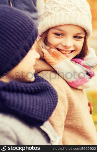 childhood, season and people concept - close up of smiling little girl and boy in autumn park