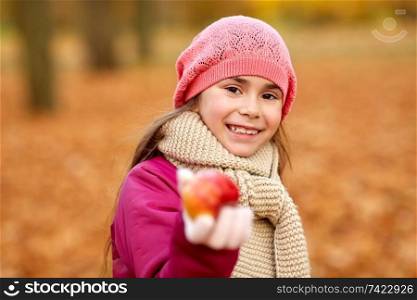 childhood, season and people concept - happy girl with apple at autumn park. happy girl with apple at autumn park