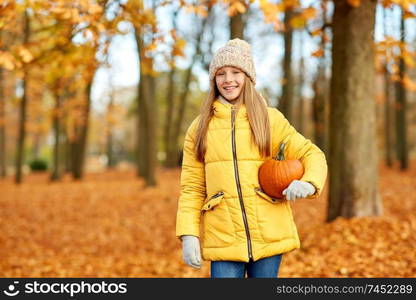 childhood, season and people concept - happy girl with pumpkin at autumn park. happy girl with pumpkin at autumn park