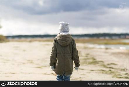 childhood, season and people concept - little girl on beach in autumn. little girl on beach in autumn