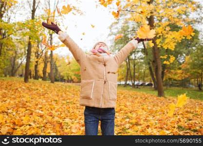 childhood, season and people concept - smiling little girl having fun in autumn park