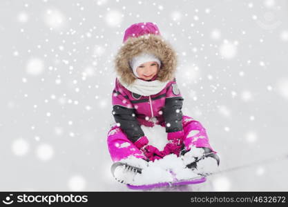 childhood, sledding, fashion, season and people concept - happy little kid on sled outdoors in winter