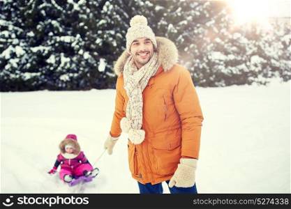 childhood, sledding, leisure, season and people concept - happy man or father carrying little kid on sled in winter. happy man carrying little kid on sled in winter